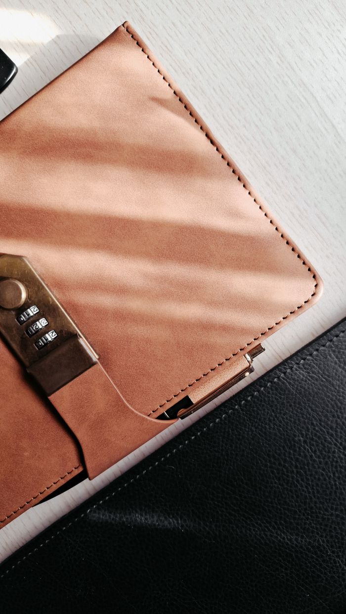 Elegant leather portfolio with a security lock, casting soft shadows on a light surface.